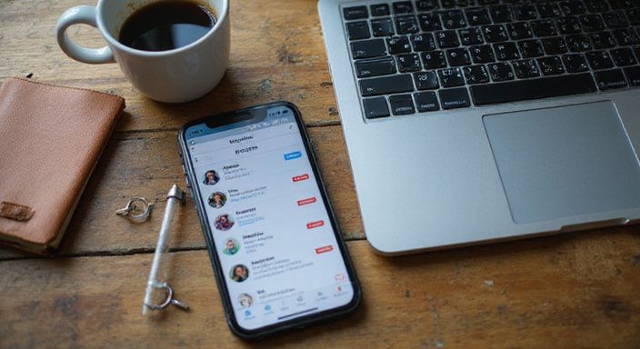 Een moderne werkplek met smartphone, laptop, koffie en notitieboek.